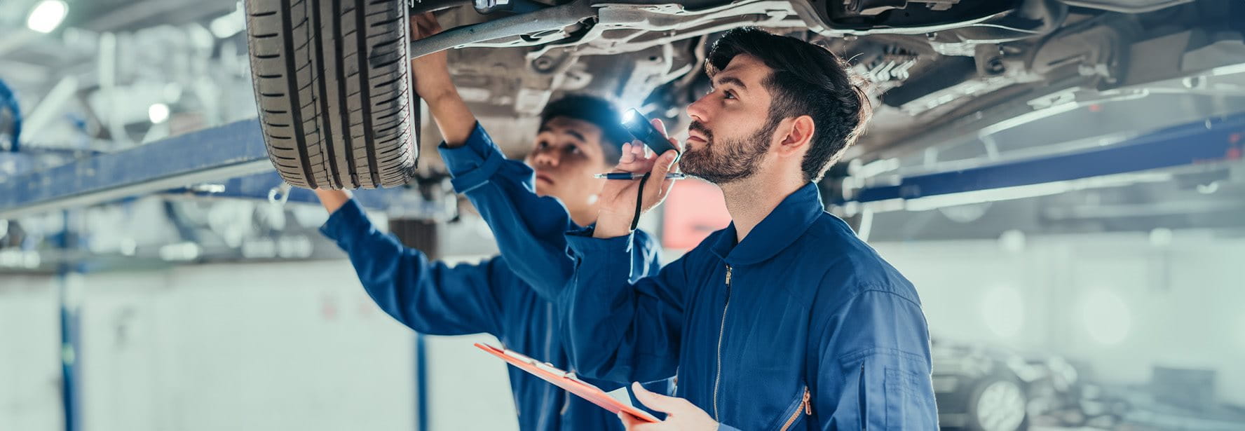 Zwei Männer in einer Werkstatt reparieren ein Auto