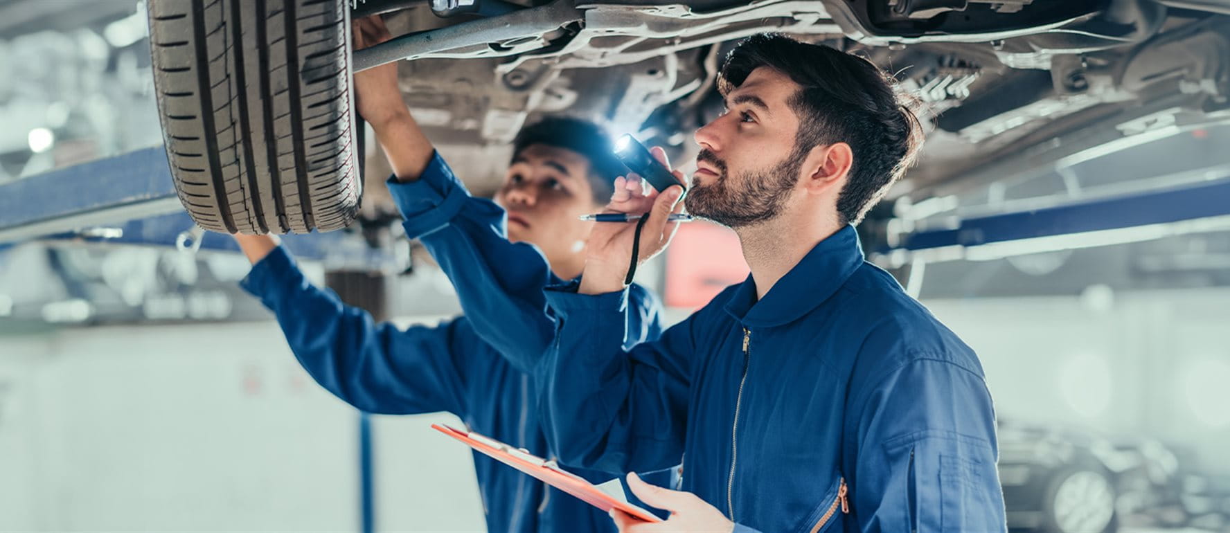 Due uomini in un garage che riparano un'auto Due uomini in un garage che riparano un'auto