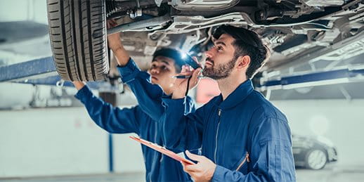 Zwei Männer in einer Werkstatt reparieren ein Auto