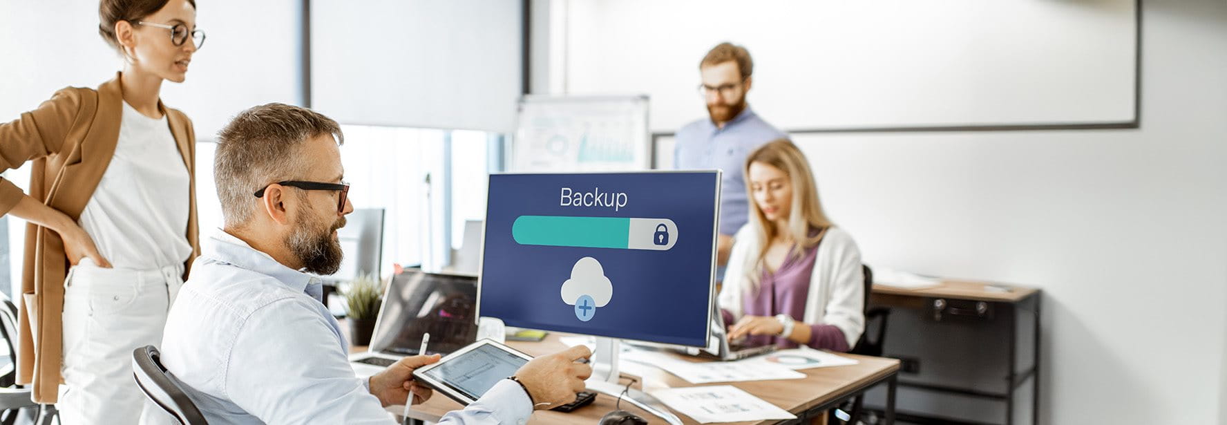 Des collaborateurs se consultent et regardent un écran d'ordinateur