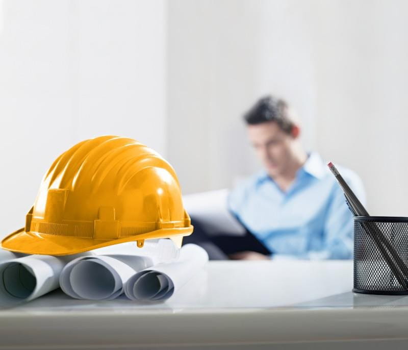 casco giallo su un tavolo e architetto sullo sfondo