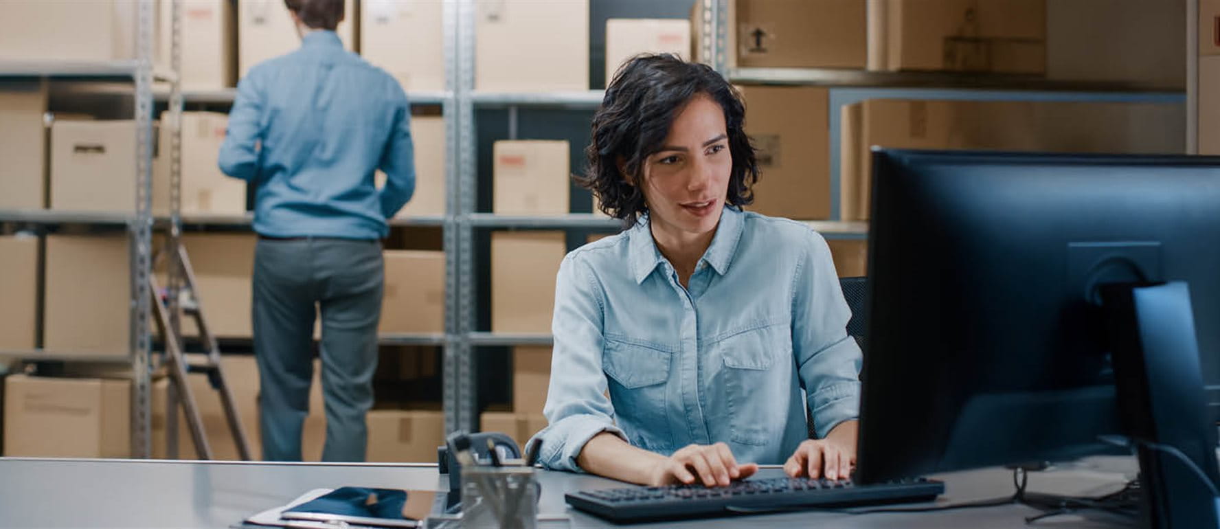 Woman sitting at a computer in a warehouse Woman sitting at a computer in a warehouse