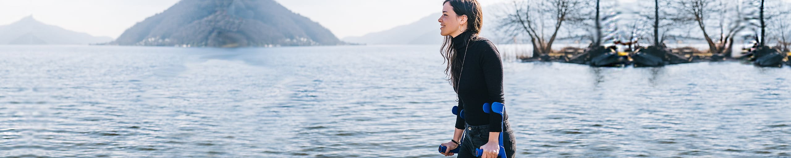 Donna cammina lungo il lago con le stampelle