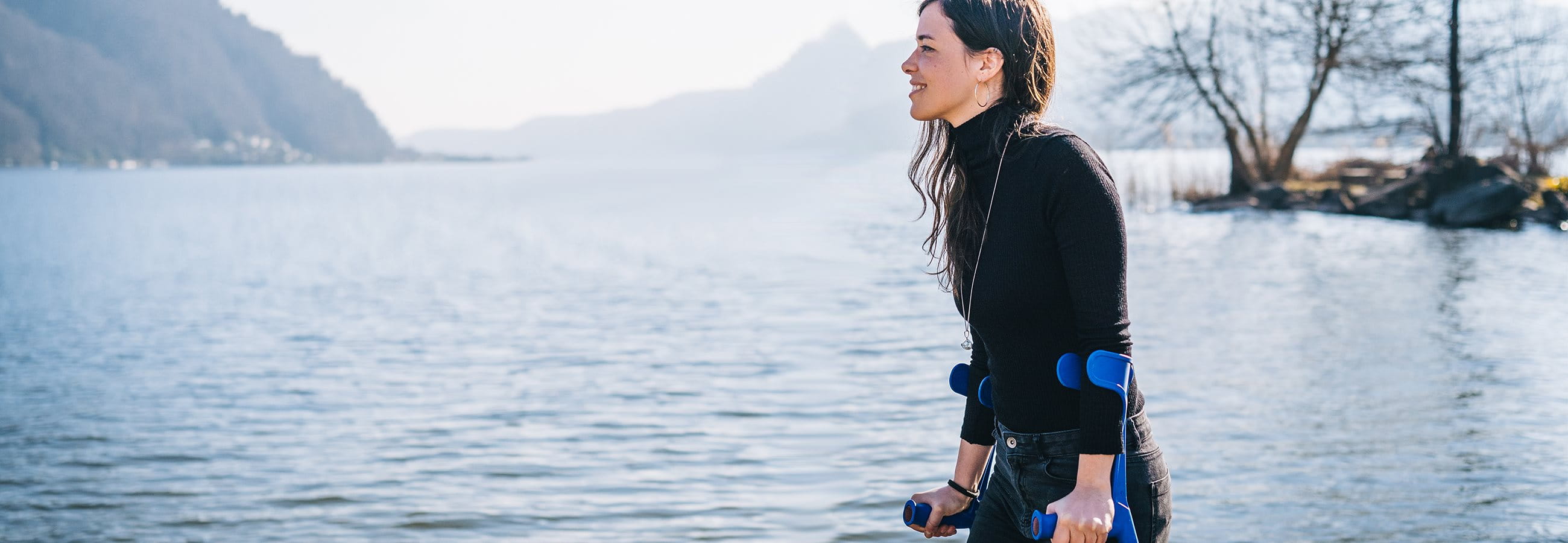 Woman walks along the lake with crutches Woman walks along the lake with crutches