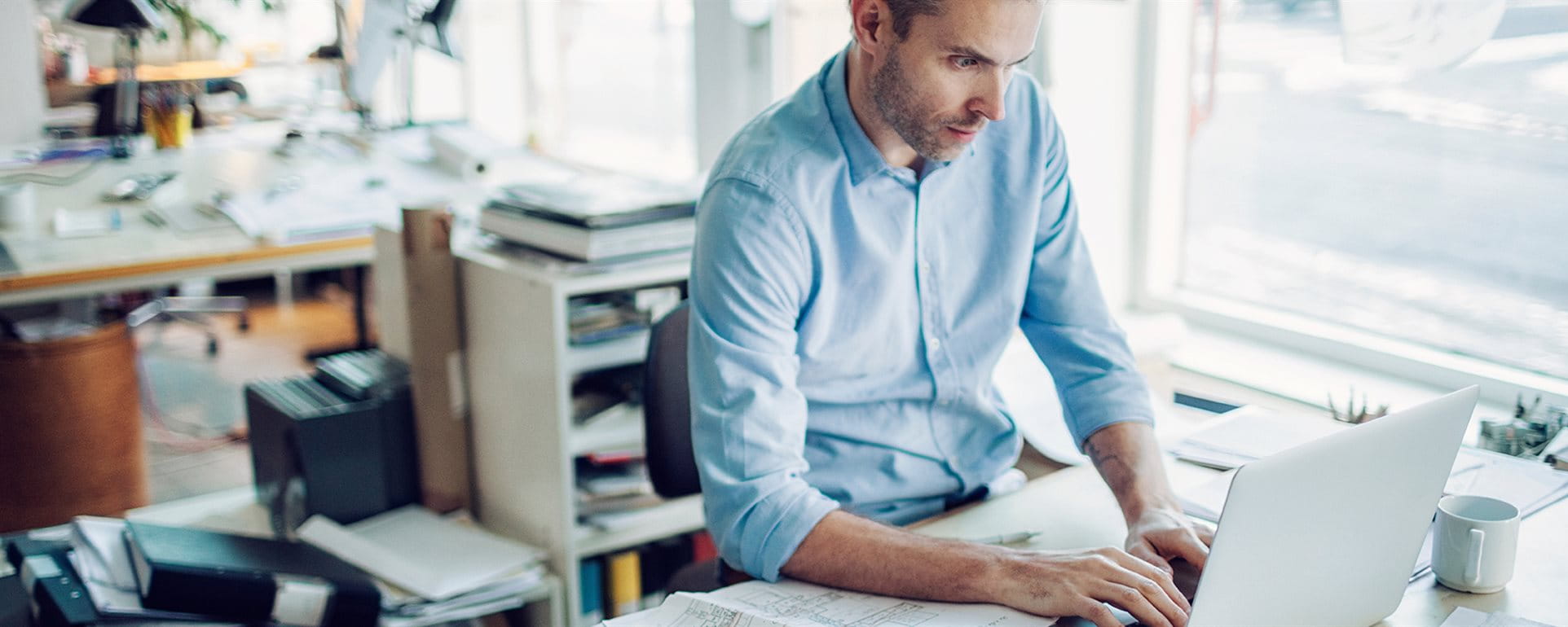 Un homme est assis à sa table de travail dans un bureau Un homme est assis à sa table de travail dans un bureau