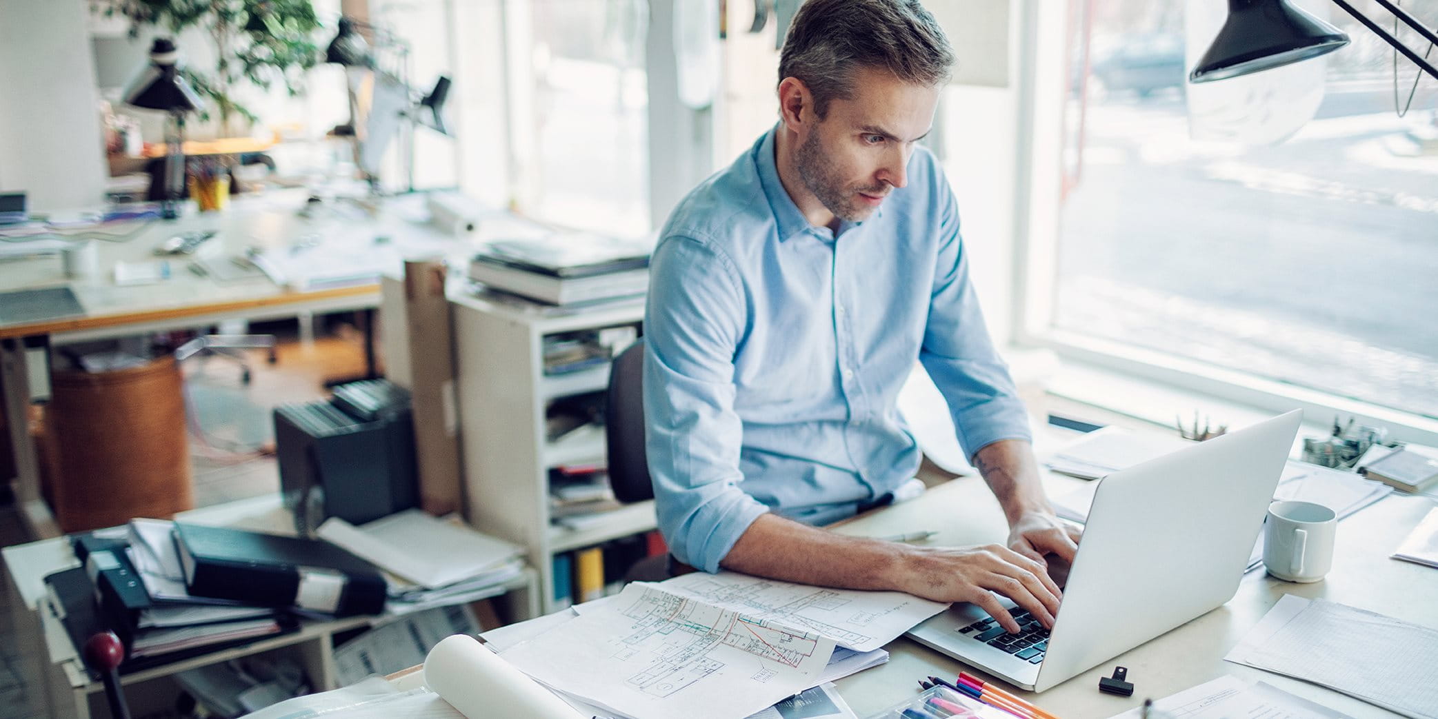 Un homme est assis à sa table de travail dans un bureau Un homme est assis à sa table de travail dans un bureau