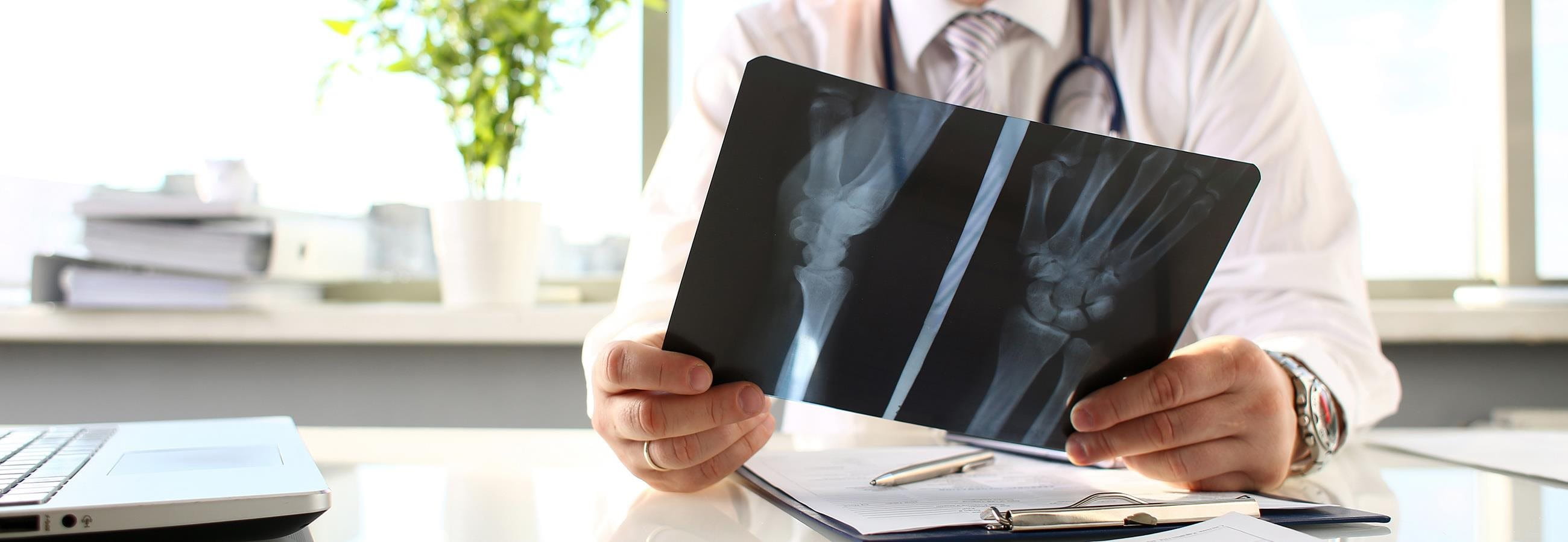 Un médecin s'assied à la table et regarde une image radiographique.