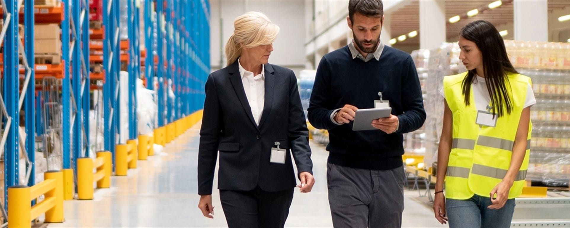 Three people are walking through a warehouse with a checklist Three people are walking through a warehouse with a checklist
