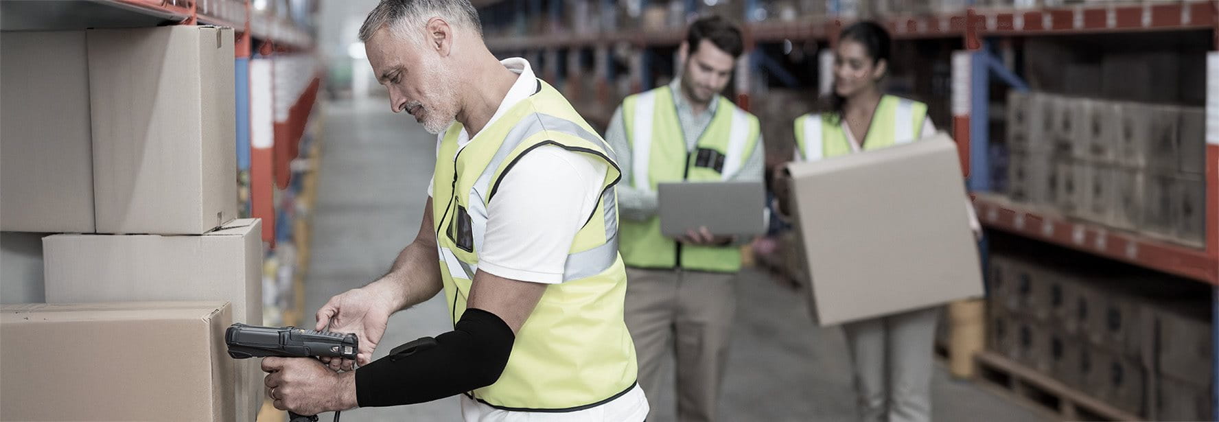 Addetto alla logistica con uno smart wearable al gomito scansiona un pacco