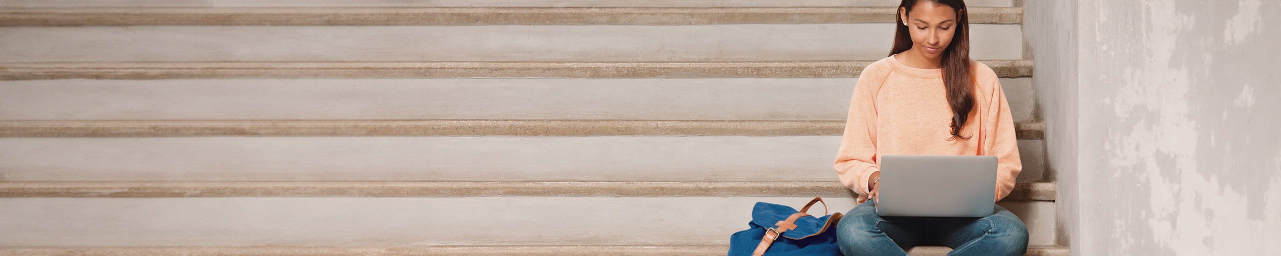 Junge Frau sitzt auf einer Treppe am Laptop