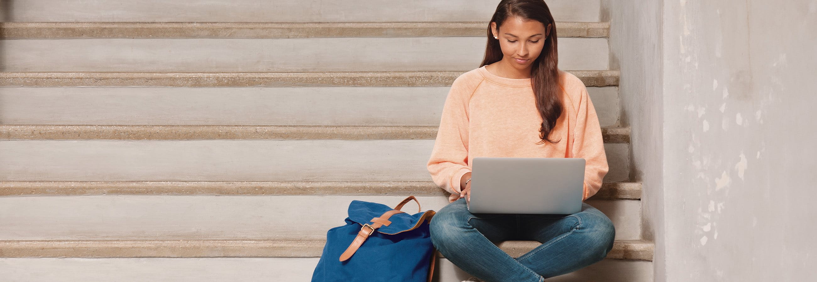 Junge Frau sitzt auf einer Treppe am Laptop