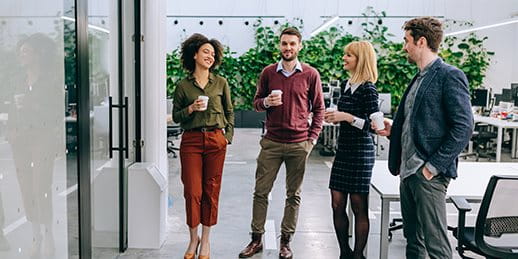 Quattro persone stanno in un moderno ufficio e tengono tazze di caffè. Quattro persone stanno in un moderno ufficio e tengono tazze di caffè.