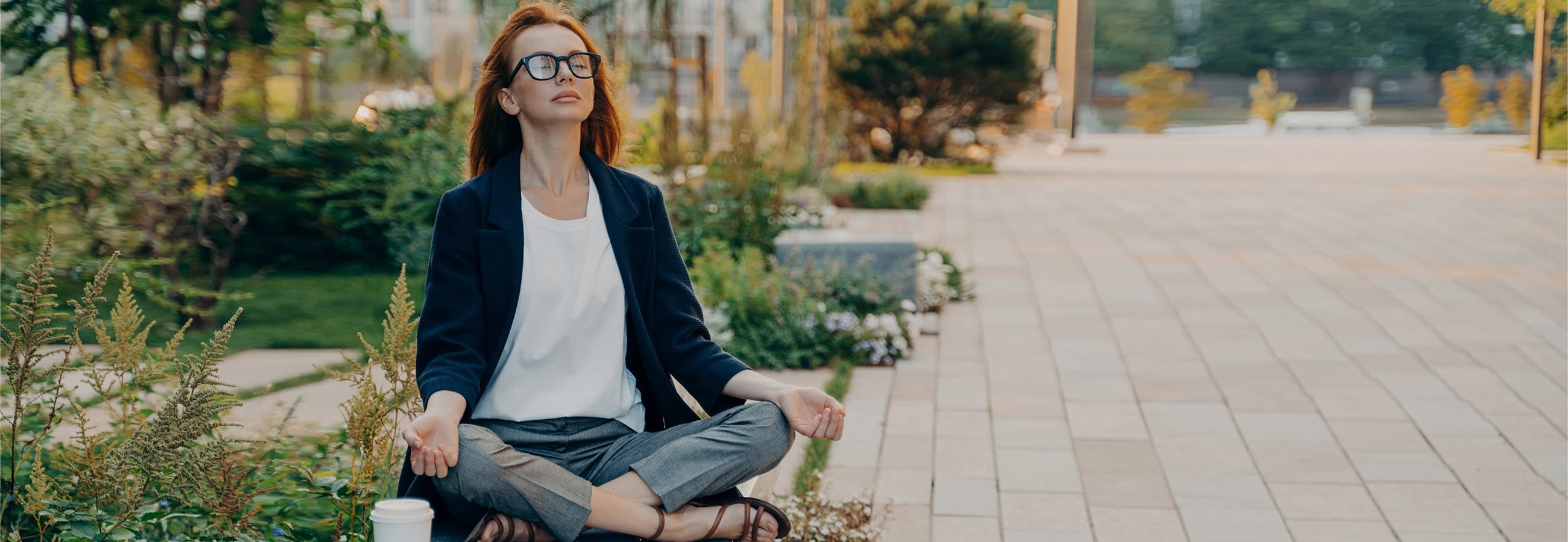  Frau sitzt im Park und macht Yoga