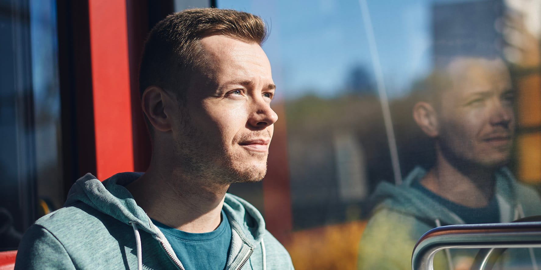 Personne assise dans les transports publics, regardant pensivement par la fenêtre.