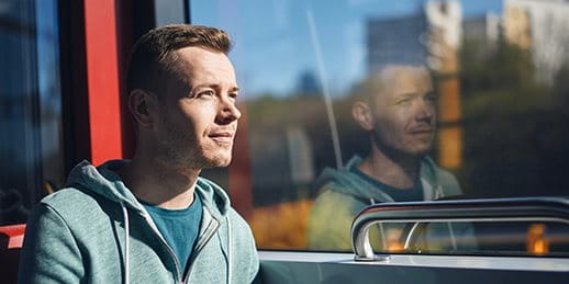 Personne assise dans les transports publics, regardant pensivement par la fenêtre.