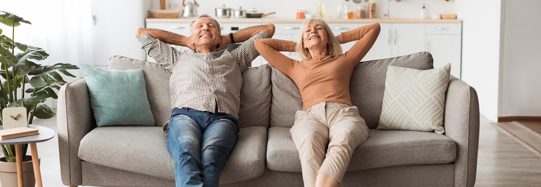 Due persone anziane sedute rilassate sul divano in soggiorno.