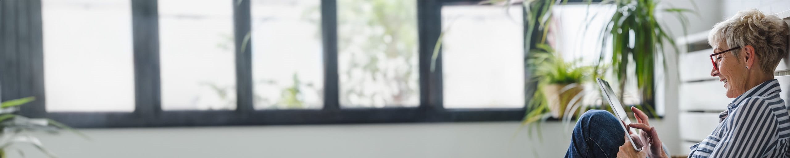 Frau sitzt mit Tablet auf dem Boden