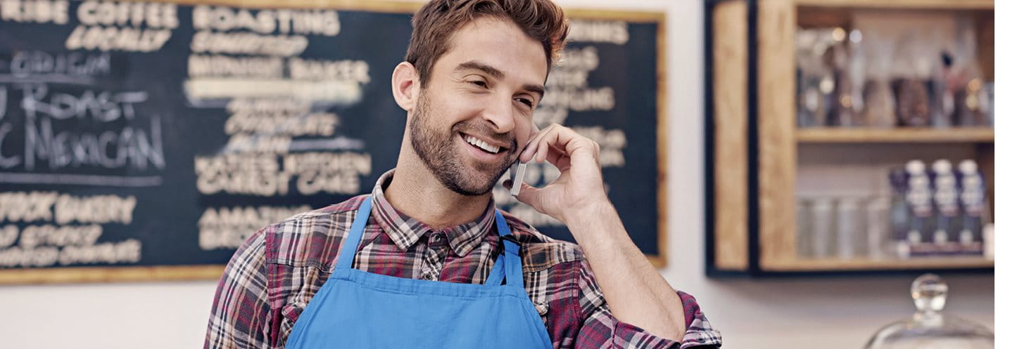 Mann steht hinter einer Bar und telefoniert