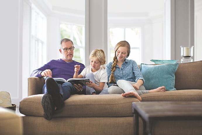 Vater sitzt mit seinen Kindern auf dem Sofa