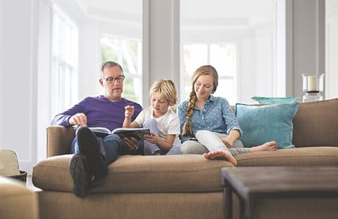 Il padre è seduto sul divano con i suoi figli  Il padre è seduto sul divano con i suoi figli