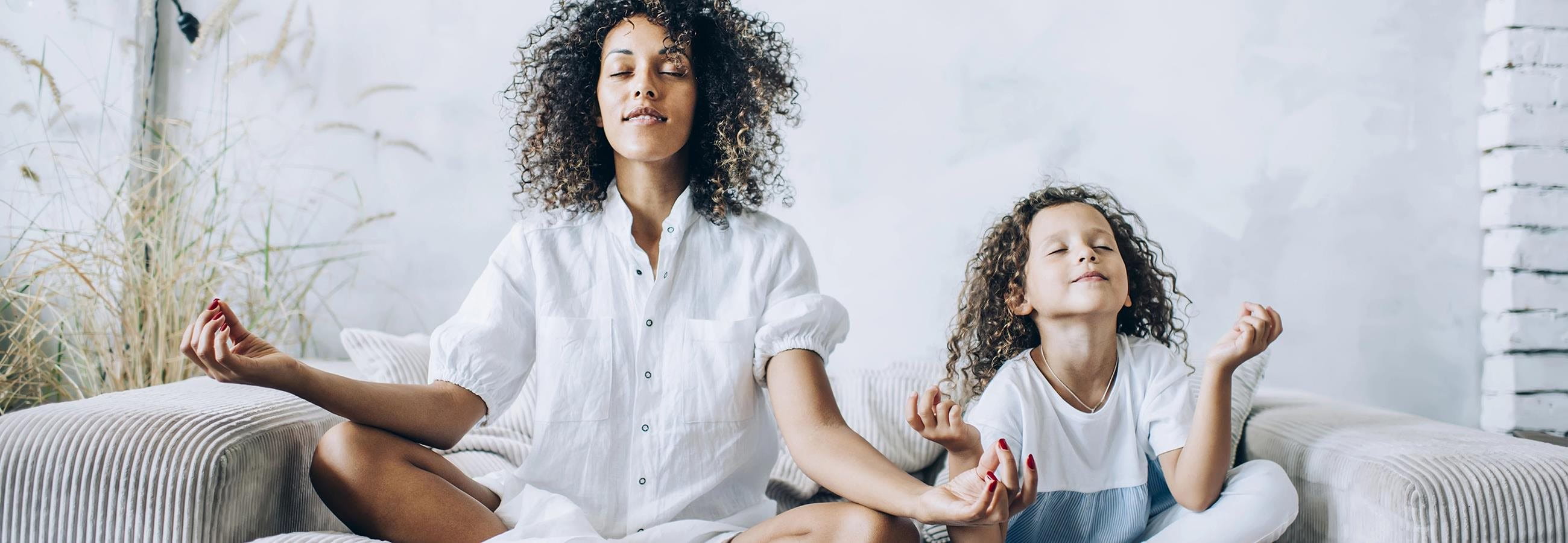 Mutter und Tochter machen Yoga auf dem Sofa Mutter und Tochter machen Yoga auf dem Sofa