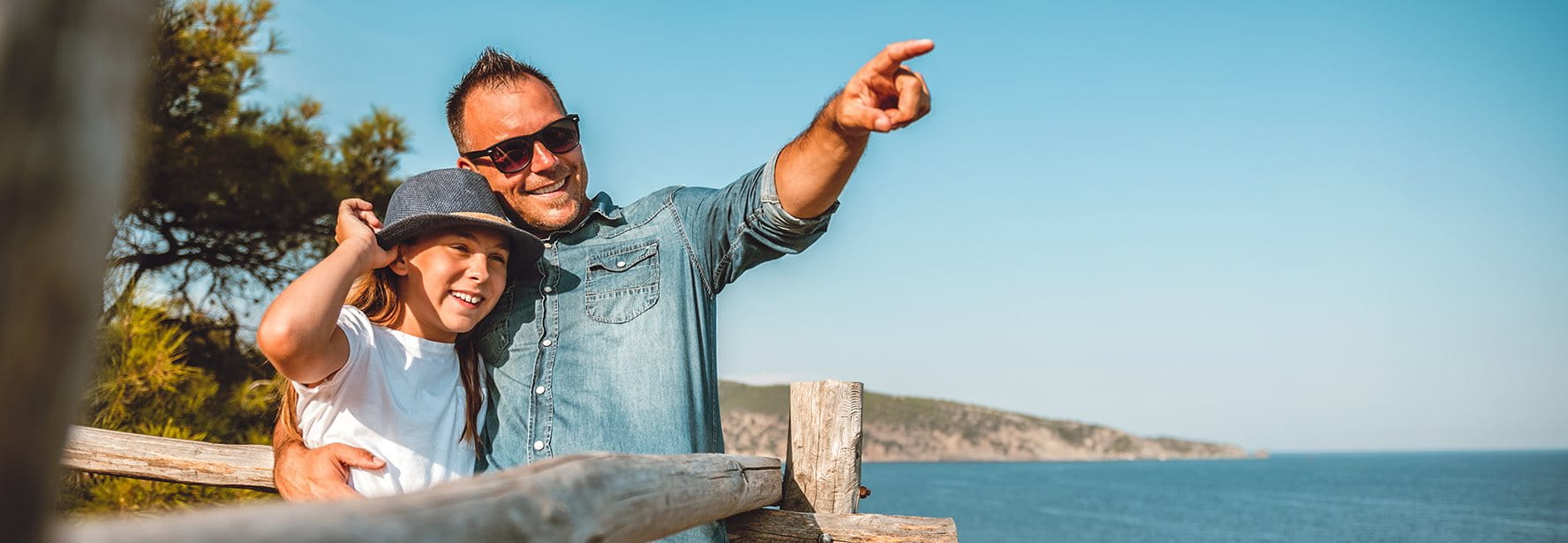 Father enjoys the view with his daughter by the sea