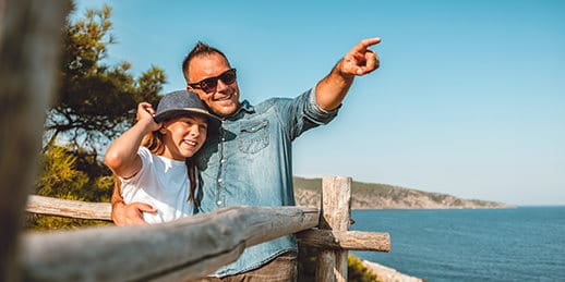 Vater geniesst Aussicht mit Tochter am Meer Vater geniesst Aussicht mit Tochter am Meer