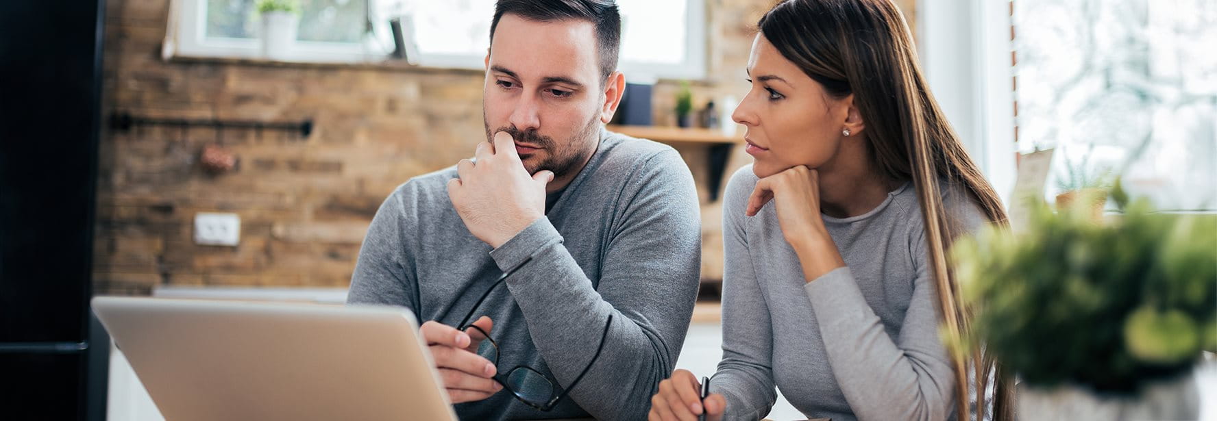 Couple sitting in front of the laptop and thinking