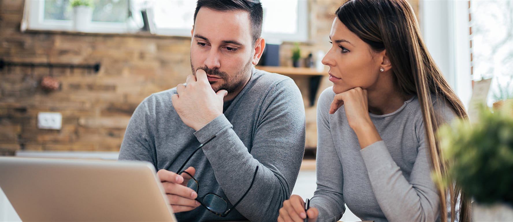 Couple sitting in front of the laptop and thinking Couple sitting in front of the laptop and thinking