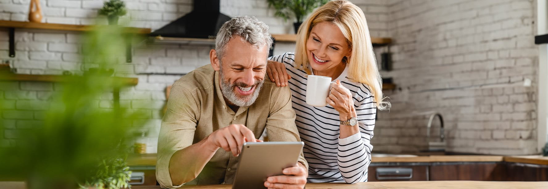 Un couple regarde quelque chose sur une tablette dans la cuisine