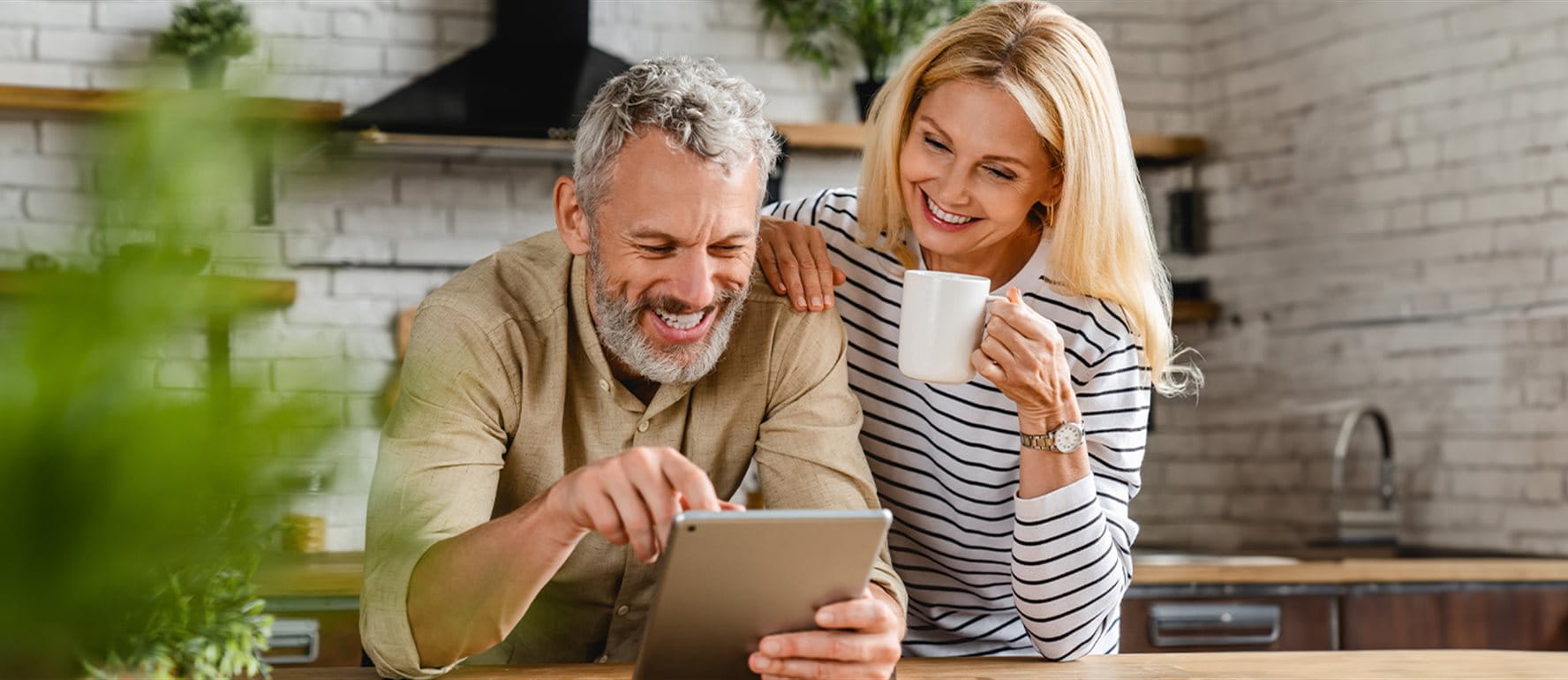 Un couple regarde quelque chose sur une tablette dans la cuisine Un couple regarde quelque chose sur une tablette dans la cuisine