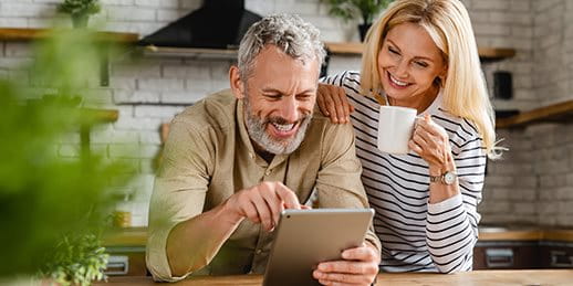 Un couple regarde quelque chose sur une tablette dans la cuisine