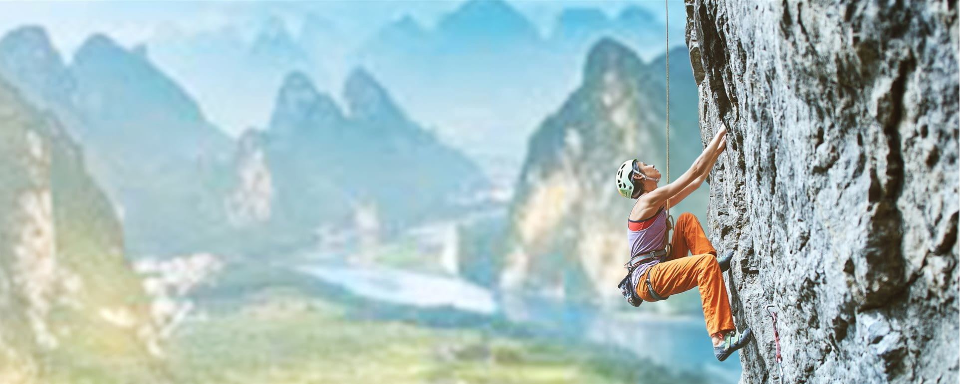 Bergsteigerin klettert an einem Fels Bergsteigerin klettert an einem Fels