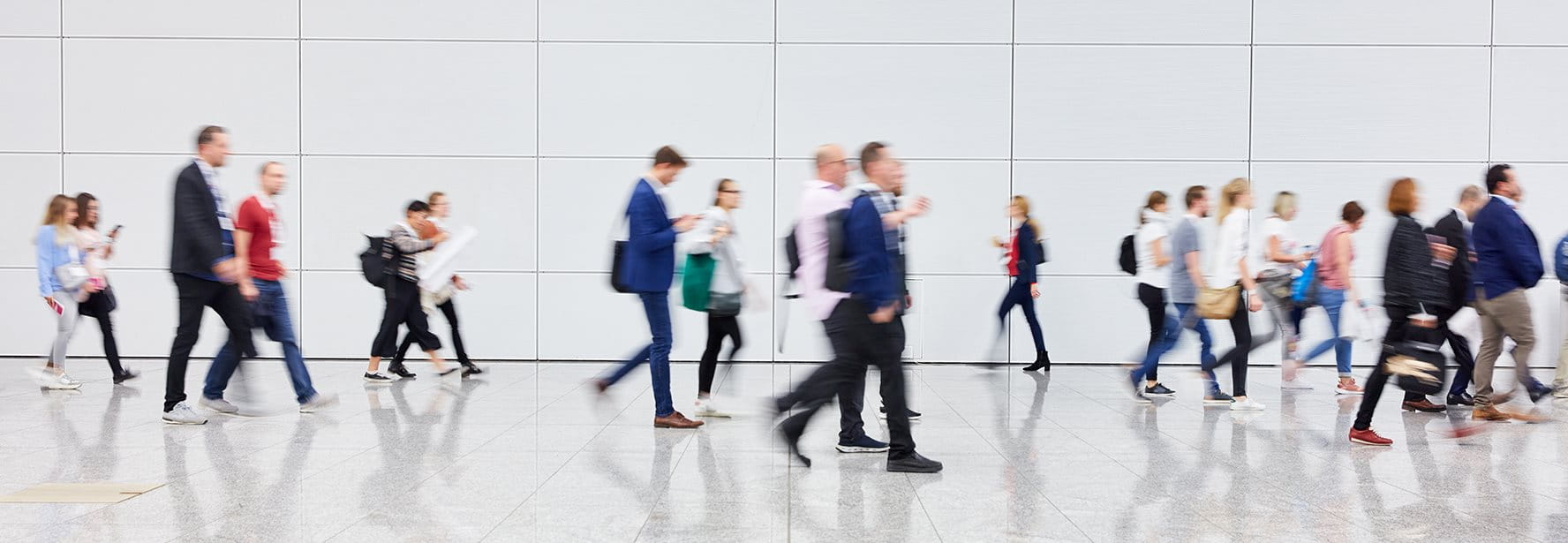 People walking in a modern, bright space with a smooth, reflective floor.