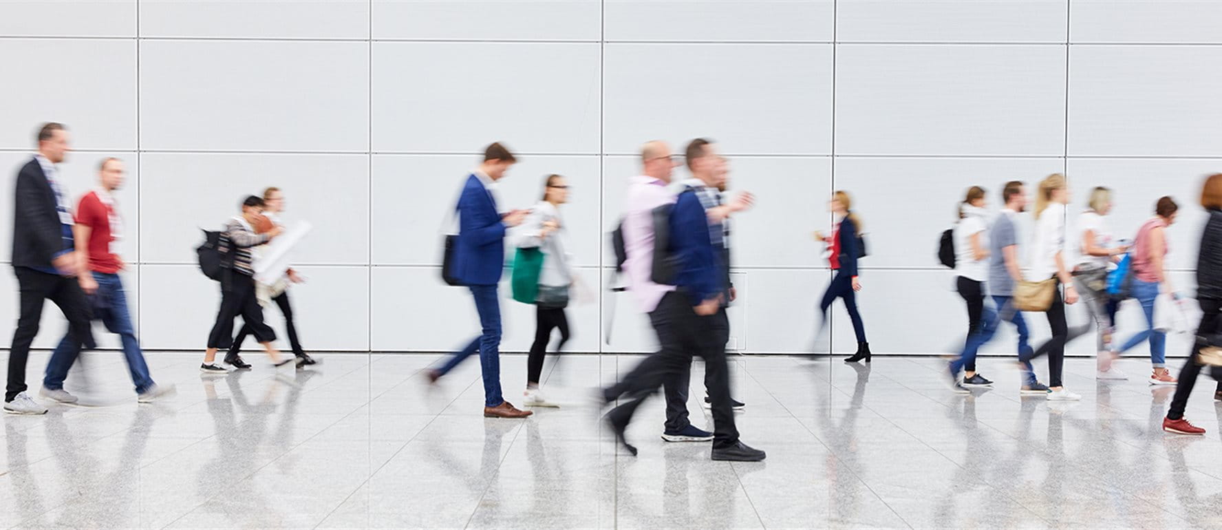 People walking in a modern, bright space with a smooth, reflective floor. People walking in a modern, bright space with a smooth, reflective floor.