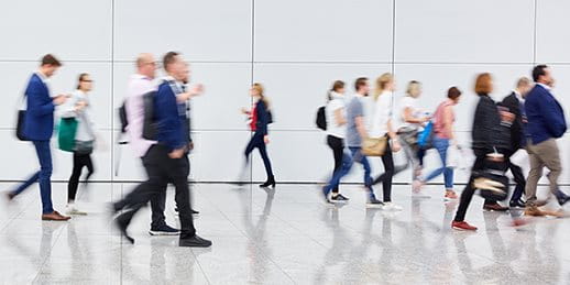People walking in a modern, bright space with a smooth, reflective floor.