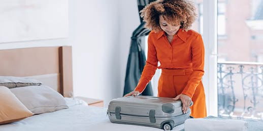 Une femme fait sa valise sur un lit