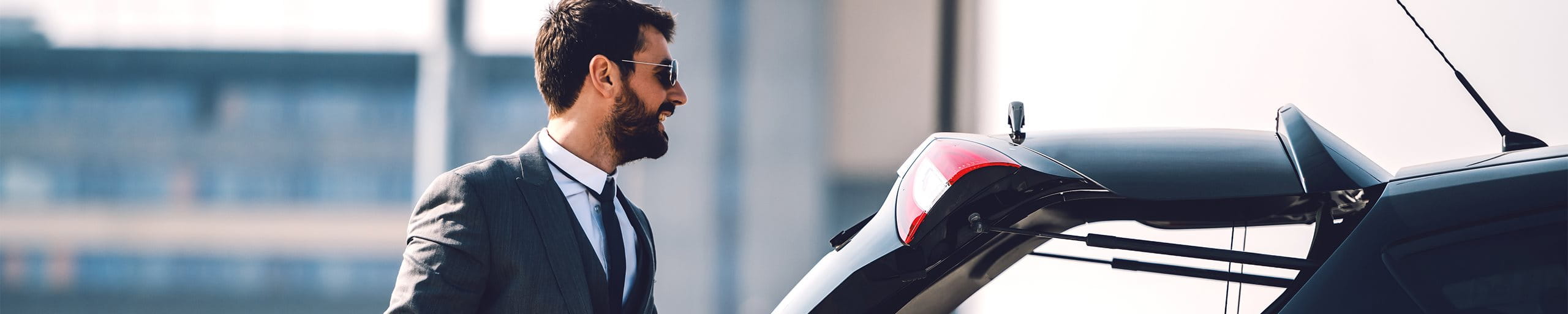 Mann steht vor dem offenen Kofferraum seines Autos