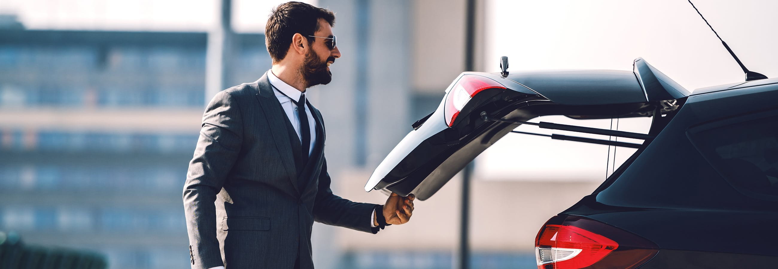 L'homme se tient devant le coffre ouvert de sa voiture L'homme se tient devant le coffre ouvert de sa voiture