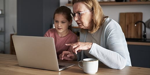 Frau sitzt mit Kind an Laptop