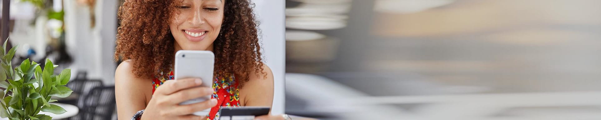 Une femme est au téléphone mobile et tient une carte de crédit dans sa main Une femme est au téléphone mobile et tient une carte de crédit dans sa main