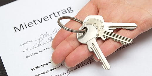 Un trousseau de clés est dans une main ouverte sur un contrat de location