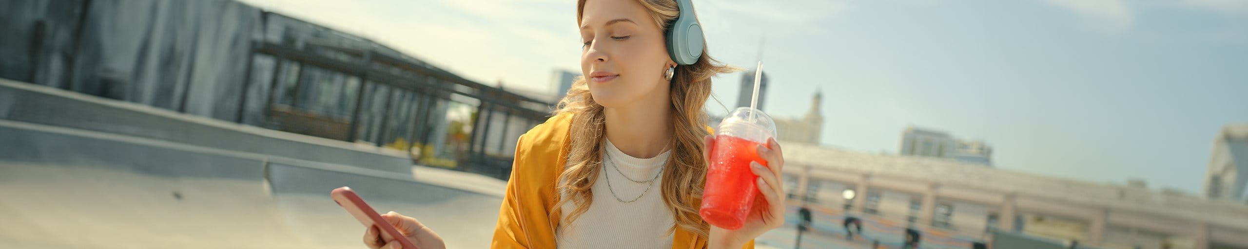 Junges Mädchen hört über Kopfhörer Musik und hält einen Icetea