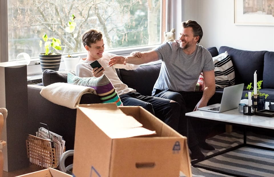 Friends resting on sofa and moving boxes standing around Friends resting on sofa and moving boxes standing around