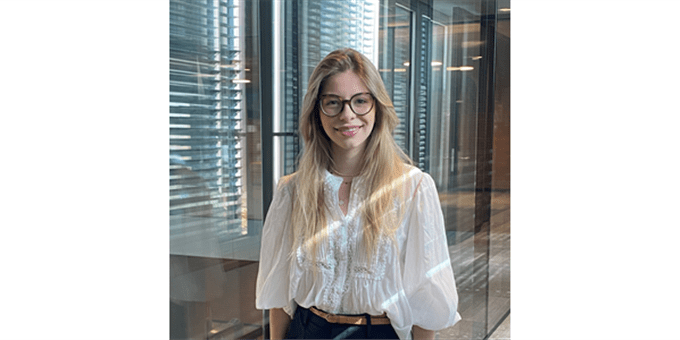 Eine Frau mit langen blonden Haaren und Brille lächelt in einem modernen Raum. Eine Frau mit langen blonden Haaren und Brille lächelt in einem modernen Raum.