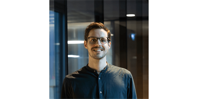 Ein Mann mit Brille lächelt in einem modernen Raum mit Glaswänden. Ein Mann mit Brille lächelt in einem modernen Raum mit Glaswänden.