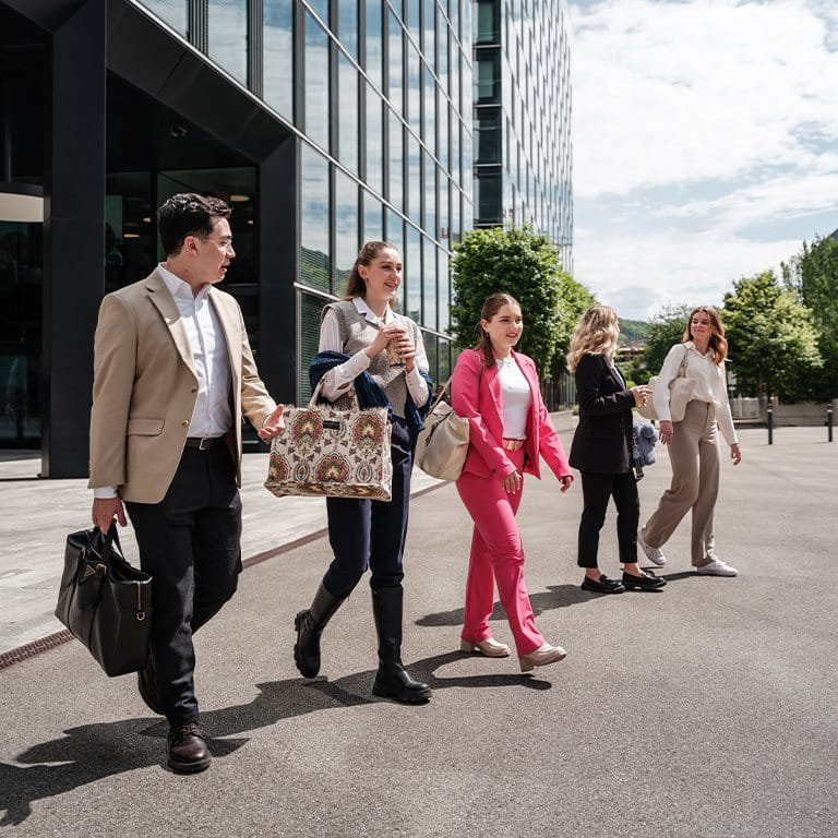 Four young people are walking out of a building.