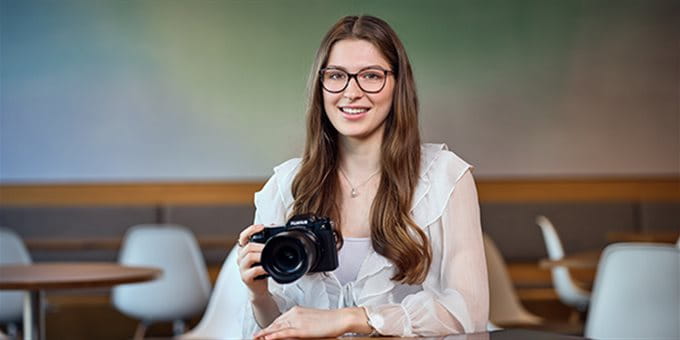 Una persona è seduta in una stanza moderna e tiene in mano una fotocamera digitale. Una persona è seduta in una stanza moderna e tiene in mano una fotocamera digitale.