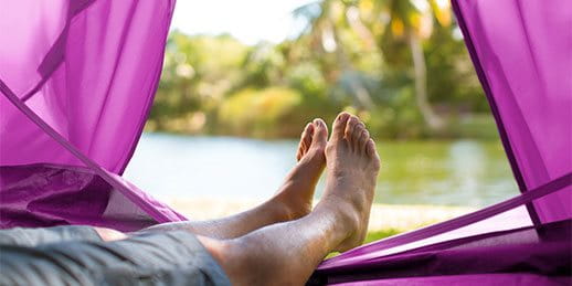 A person in a tent looking at a lake