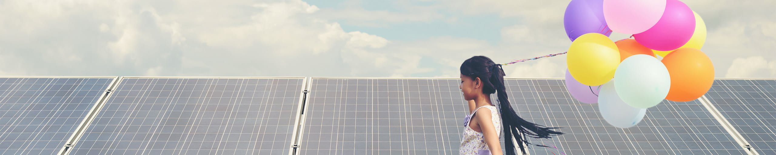 Kind mit Luftballons vor Solarpanels